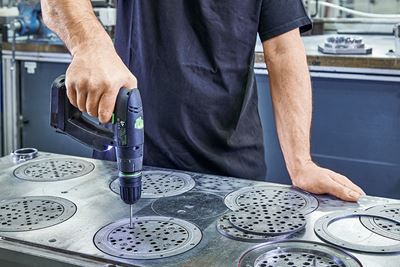 Un ouvrier perce des plaques abrasives métalliques