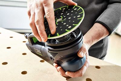 Un artisan installe le plateau de ponçage sur une ponceuse Festool